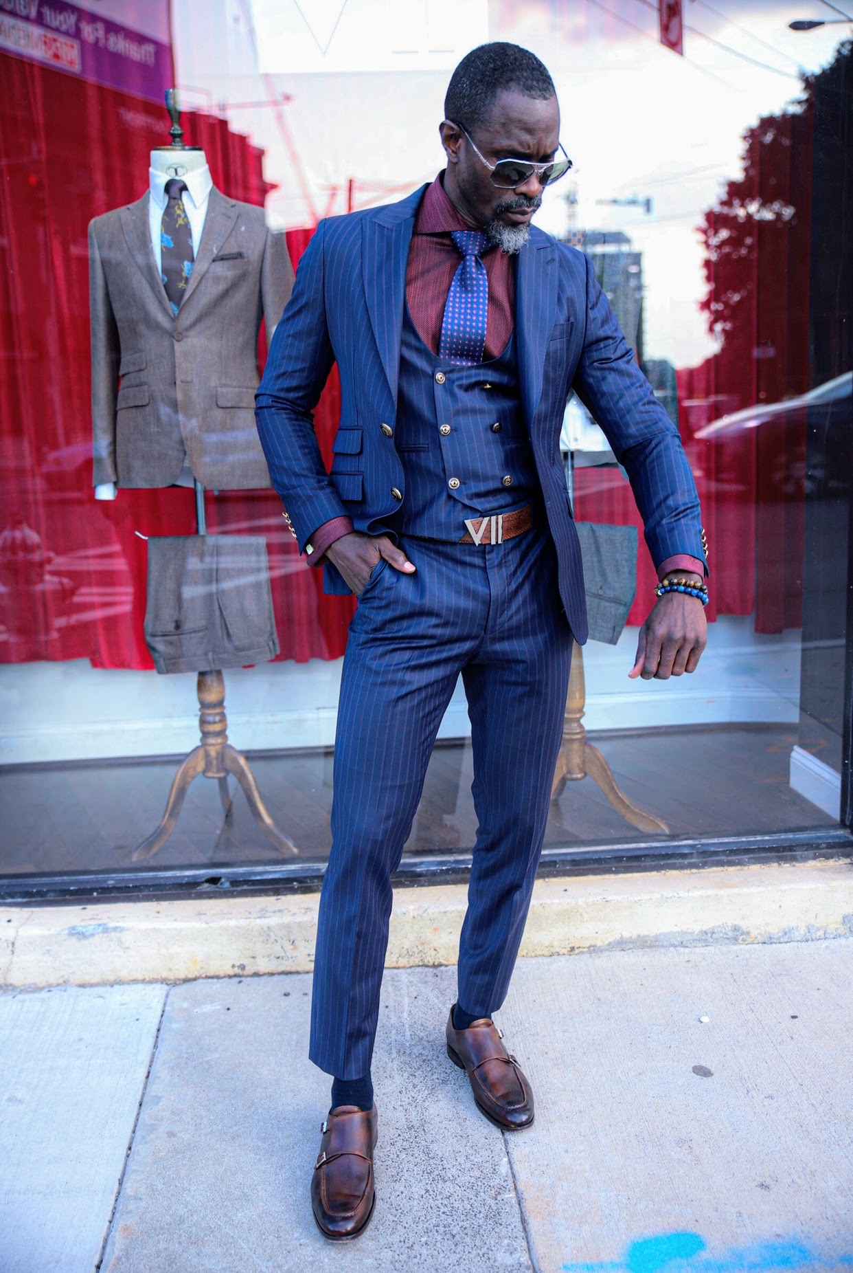 Amistad wearing a navy pinstripe suit and sunglasses